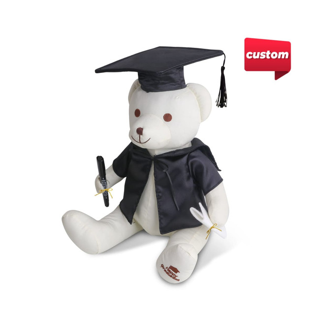 A plush bear in a black graduation cap and gown, holding a pen, with a branding logo on the side.