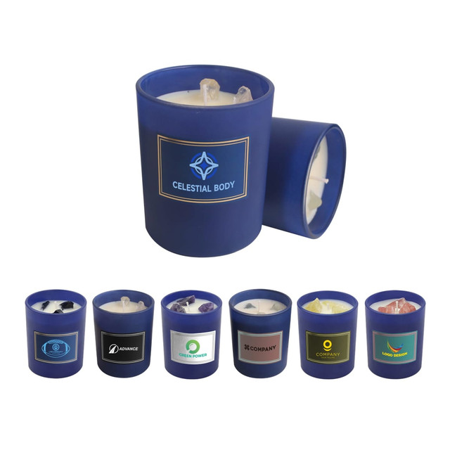 A 6.6oz blue glass candle with a white wax interior and gemstones on top, alongside various other candles in different colours. A 6.6oz blue glass candle with a white wax interior and gemstones on top, alongside various other candles in different colours.
