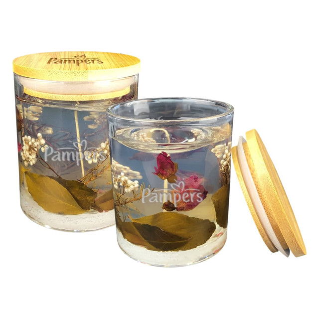 A floral candle in a glass jar, filled with preserved flowers and greenery, featuring a wooden lid. A floral candle in a glass jar, filled with preserved flowers and greenery, featuring a wooden lid.