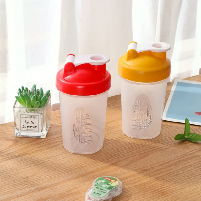 A drink bottle set featuring a red shaker and a yellow shaker, both with screw-on lids and a logo. A drink bottle set featuring a red shaker and a yellow shaker, both with screw-on lids and a logo.