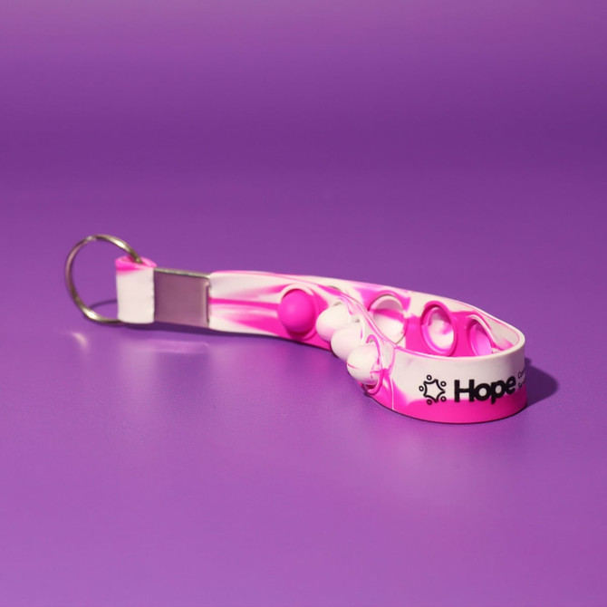 A pink and white Popper Stress Reliever Key Chain featuring round poppers and a keyring attachment.