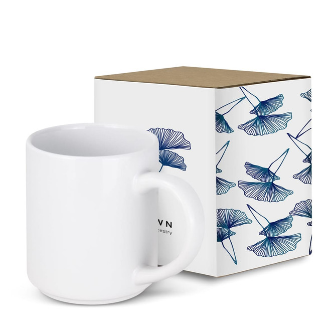 A stackable white coffee mug next to a decorative box featuring blue floral designs. The box has a logo.