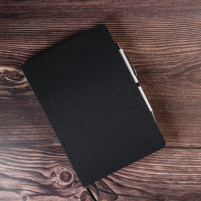 A black A5 notebook with a pen holder, featuring a minimalist design and a textured cover.