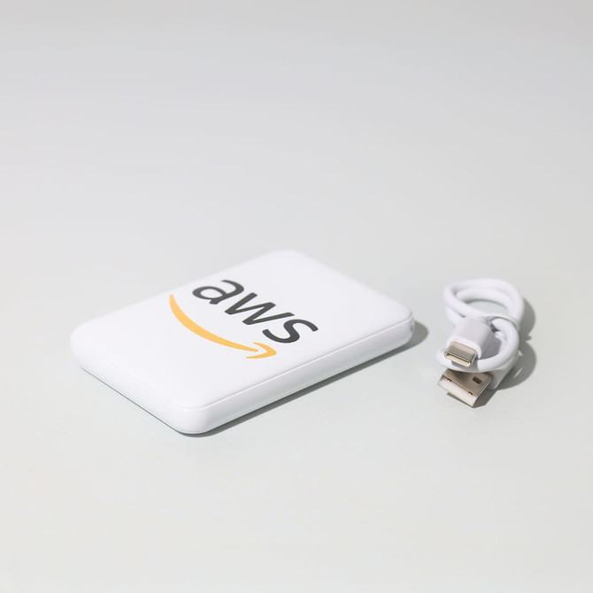A white powerbank with a logo and a small USB cable beside it.