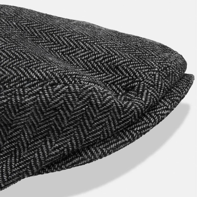 A flat cap featuring a herringbone pattern in shades of grey, with a rounded top and a small brim.
