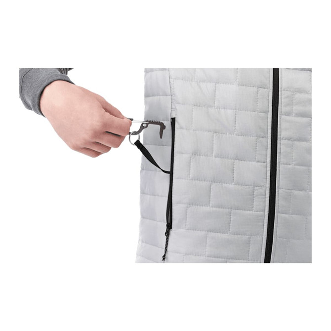 A hand pulls a key clip from a zip pocket on a grey insulated puffer vest. The vest features a quilted design.