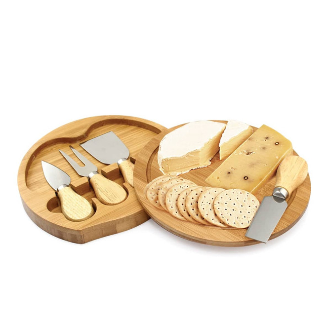 A cheese set featuring five stainless steel utensils on a bamboo platter with assorted cheeses and crackers.
