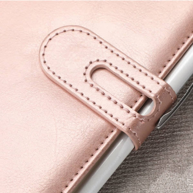 A pink PU notebook with a stitched closure and a metallic accent, featuring a branded logo.