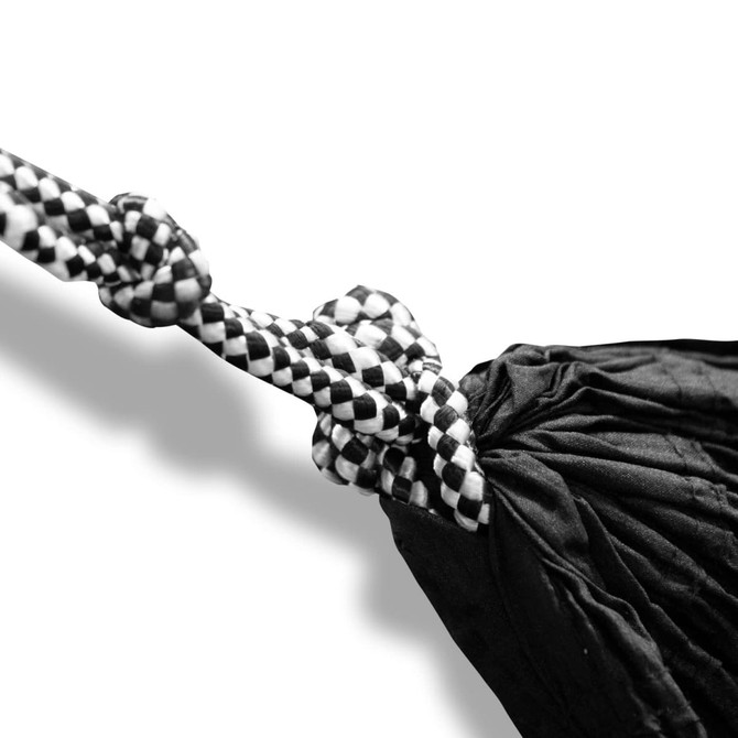 A black and white hammock with intricate knotting details, featuring a checkered pattern on the rope.