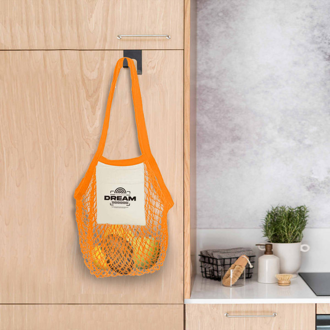 A mesh foldaway cotton tote bag in orange, hanging from a hook, containing yellow fruits. It features a logo.