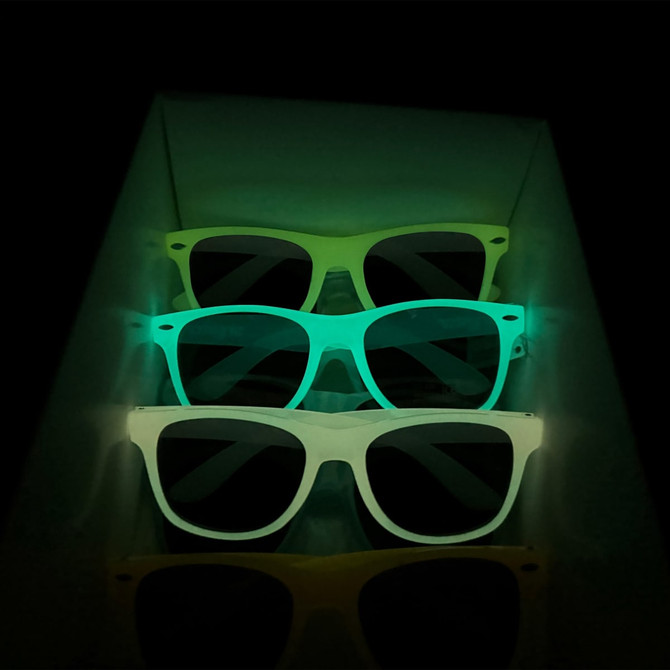 Glow in the dark sunglasses in green shades, stacked inside a display box. The sunglasses emit a soft glow in the dark.