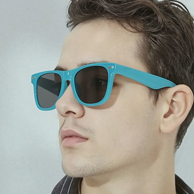 A pair of turquoise sunglasses with dark lenses, displayed on a model's face. The sunglasses feature a branding logo.