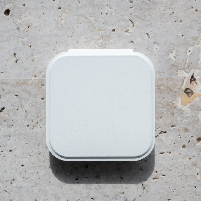 A white compact mirror with an LED light, featuring a square shape and a smooth surface, resting on a textured stone background.