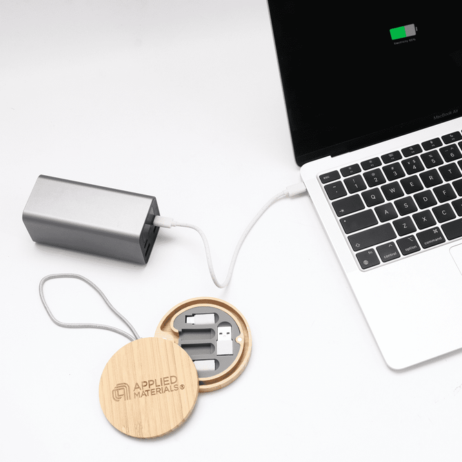 A bamboo circular cable kit with multiple connectors, connected to a silver power bank and a laptop.
