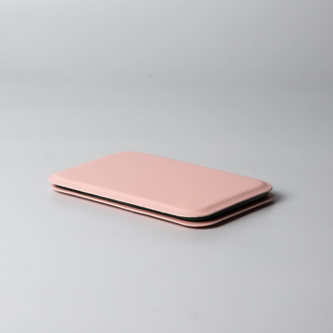 A pink pocket mirror with a slim, rectangular design, featuring a smooth surface and rounded edges.