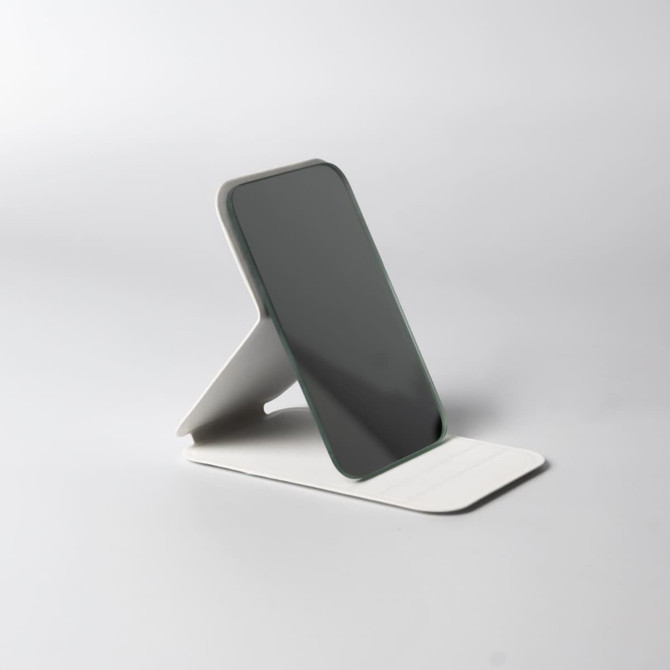 A compact, sleek pocket mirror in grey, with a sturdy white stand for easy positioning. It features a logo.