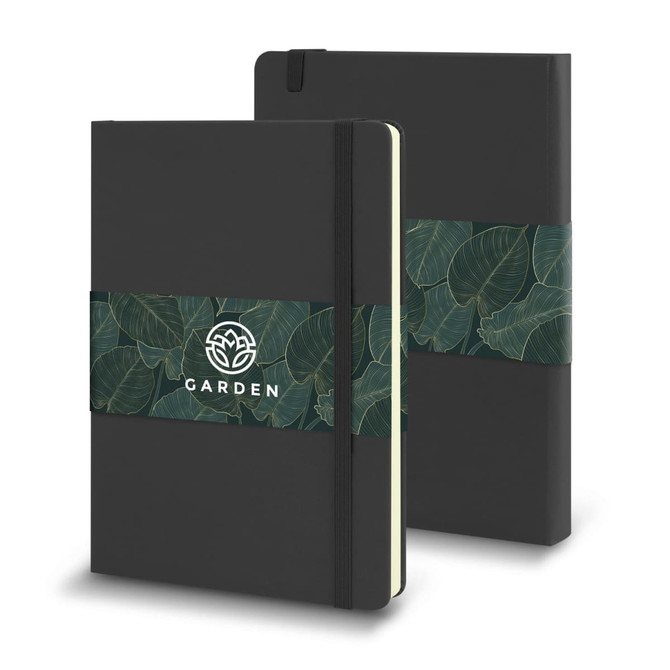 A large, black Moleskine Classic Hard Cover Notebook with a green leaf-patterned band and an emblem.
