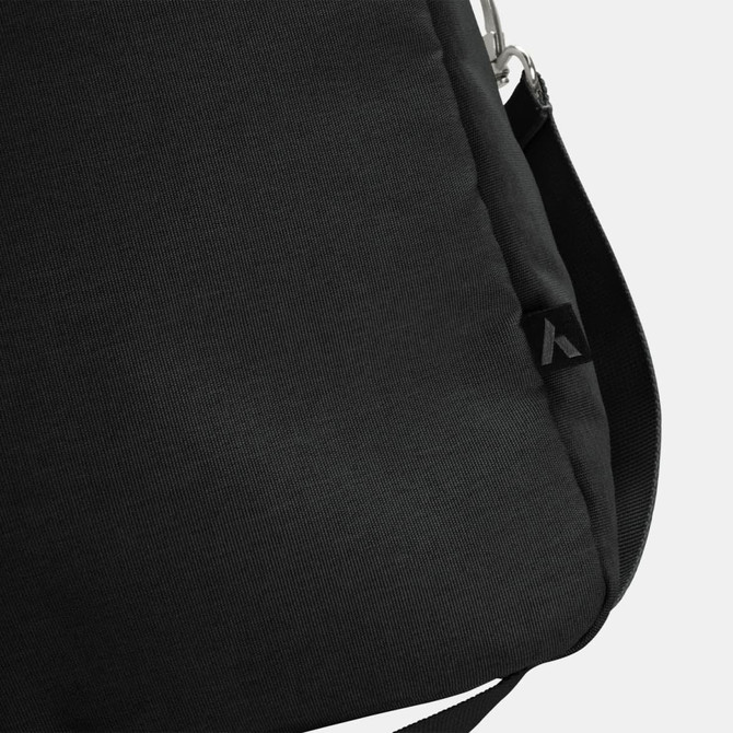 A black duffle bag with a subtle texture and an attachment point for a strap, featuring a small logo.