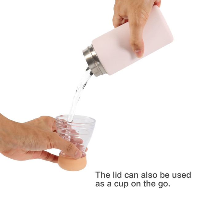 A drink bottle in soft pink, pouring liquid into a clear cup. It has a stainless steel lid that doubles as a cup.