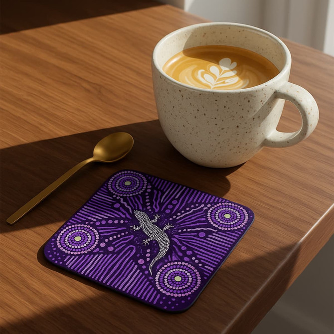 A purple square coaster featuring a lizard design, placed beside a speckled coffee cup on a wooden table.