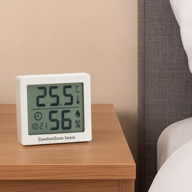 A white digital thermometer displays temperature at 25.5°C and humidity at 56%, placed on a wooden bedside table.