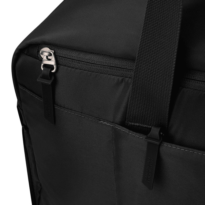 A black duffle bag corner with zippers and webbing straps, featuring a subtle logo on the surface.