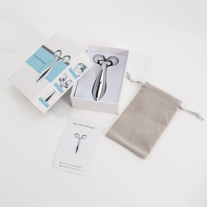 A silver facial roller with a storage pouch and instructions, presented in a sleek white box.