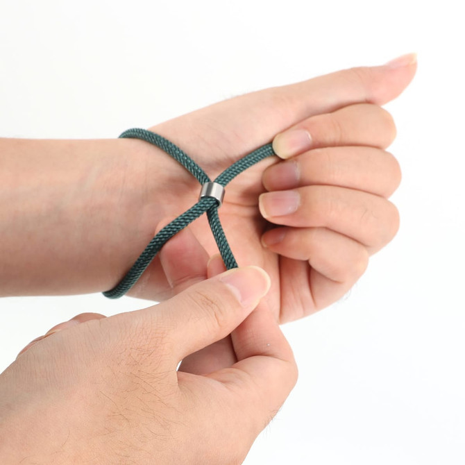 A green metal woven bracelet is being adjusted on a person's wrist, showcasing its flexible design.