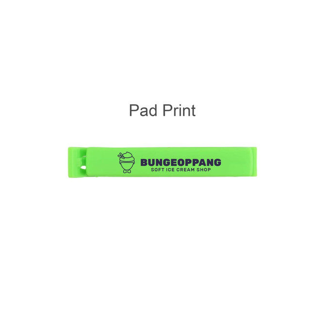 A green food bag seal clip with a logo on one side, featuring a simple graphic and text design.