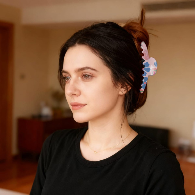 A hair clip in pastel pink and blue patterns worn in a woman's dark hair, styled with a simple black top.
