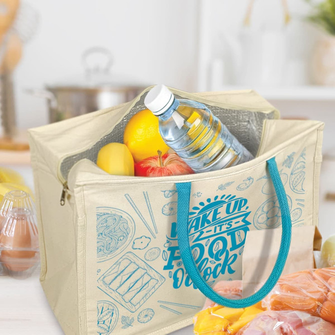 A cooler bag in cream with teal handles, filled with a drink bottle, fruits, and a variety of food items.