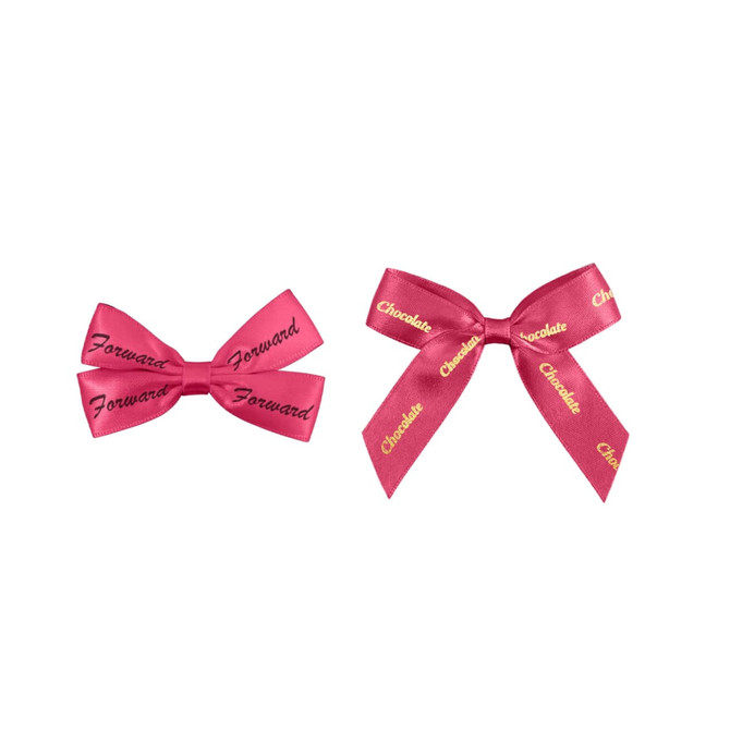 Two pink adhesive bows displayed side by side, with text printed on them. One is smaller, the other larger.