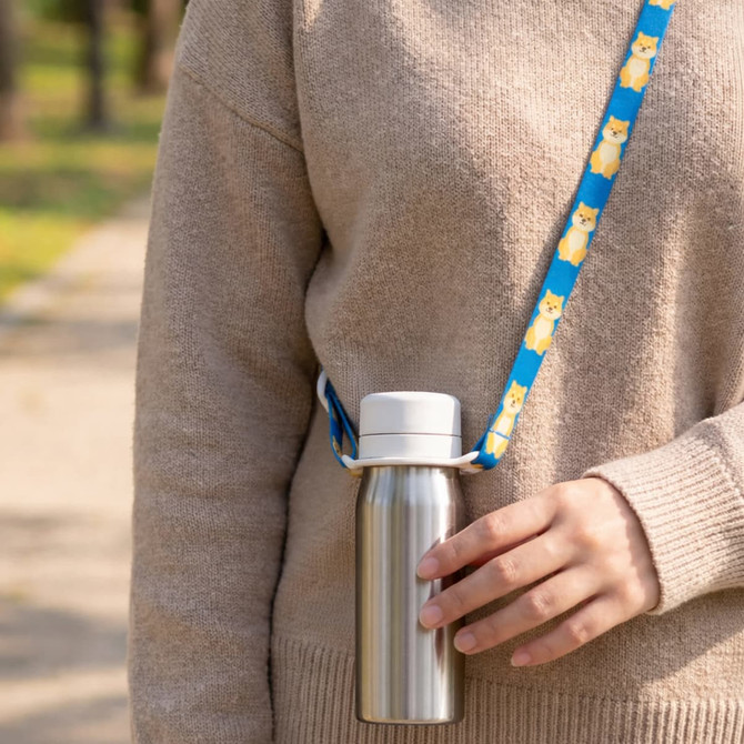 A drink bottle with a silver metallic finish and a blue lanyard featuring a pattern of cute animals.