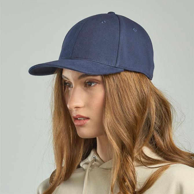 A navy blue cap with a curved brim, featuring a logo on the front, worn by a model with long hair.