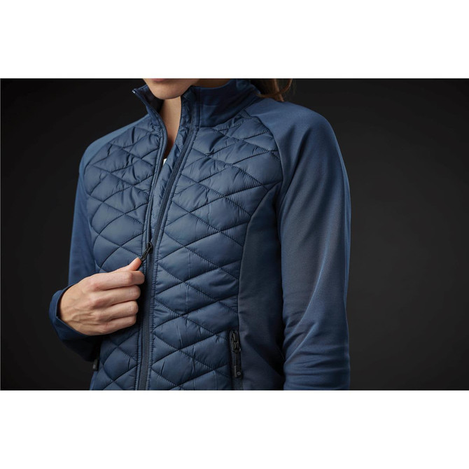 A women's thermal shell jacket in navy blue featuring a quilted design and side pockets. Includes a logo.