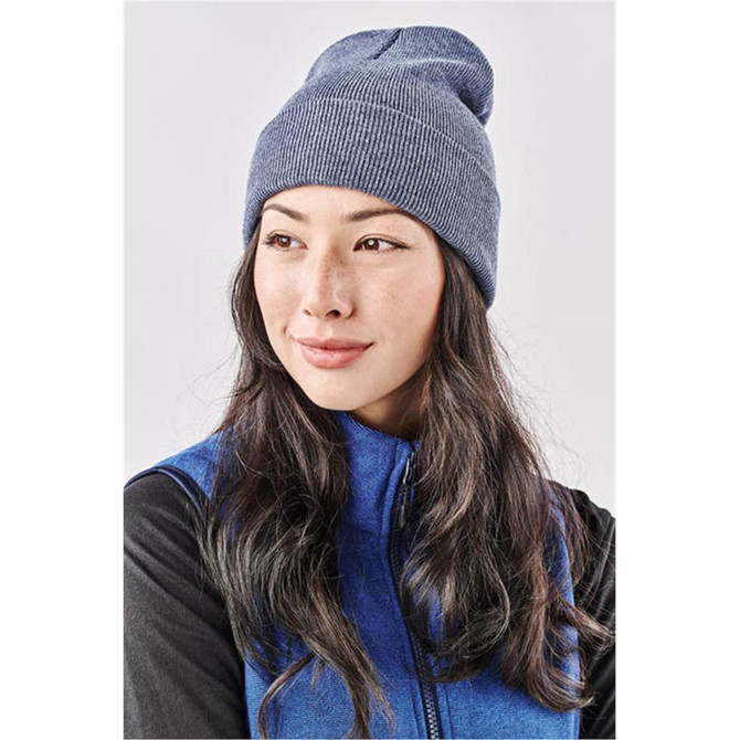 A blue knit beanie worn by a woman with long, dark hair, featuring a logo on the front.