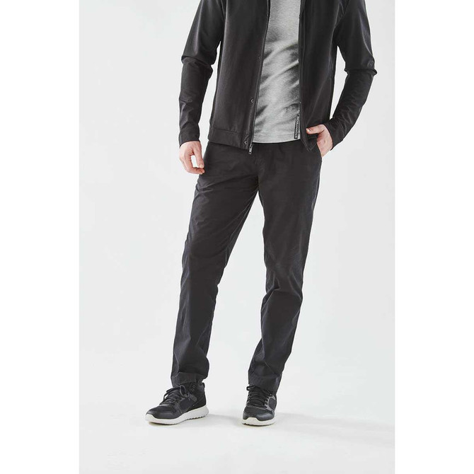 Men's Soho Performance Pant in black, featuring a sleek design and a logo, styled with a grey top and black shoes.