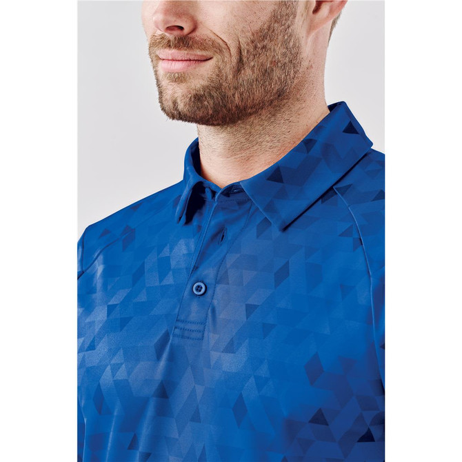 A close-up of a men's polo shirt in blue featuring a geometric pattern and a collar. The shirt has a logo.