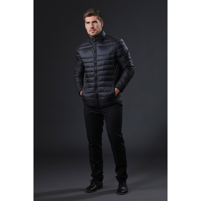 A stylish black puffer jacket displayed on a model standing against a dark background, featuring a logo on the chest.