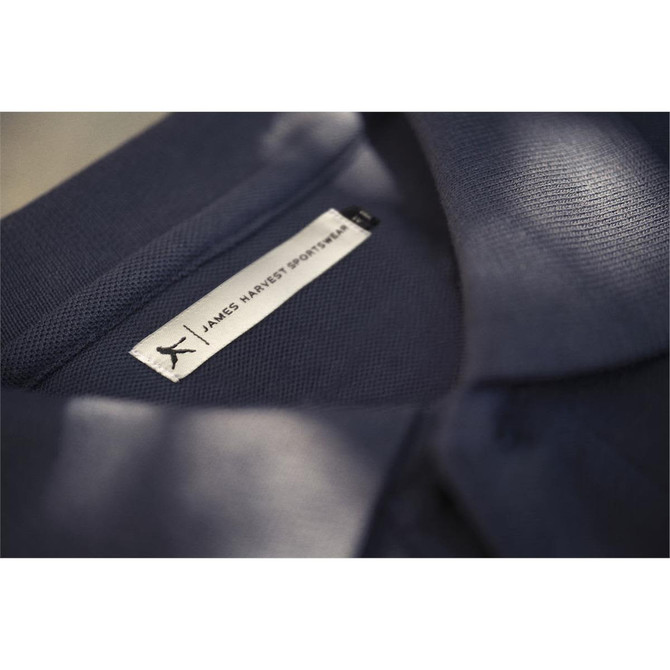 A close-up of a navy blue cotton polo shirt featuring a label with a logo.