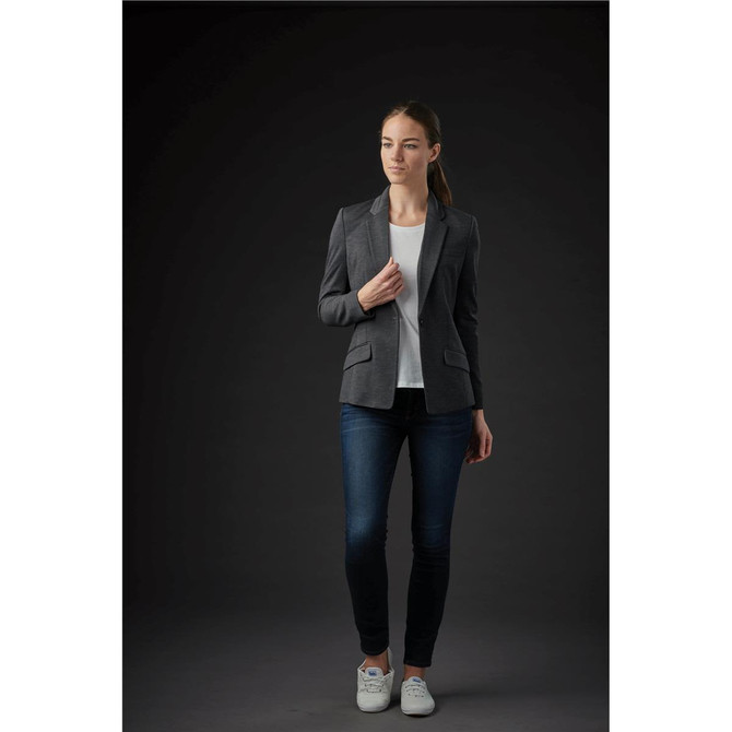 A grey women's knit blazer with a fitted silhouette, styled with a white top and dark jeans. The model wears white sneakers.