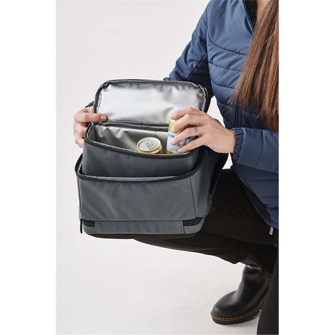 A grey backpack with a silver insulated interior, held open by a person while showcasing its storage space.