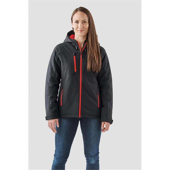 A woman wearing a black and red insulated softshell jacket with a hood and multiple zip pockets.