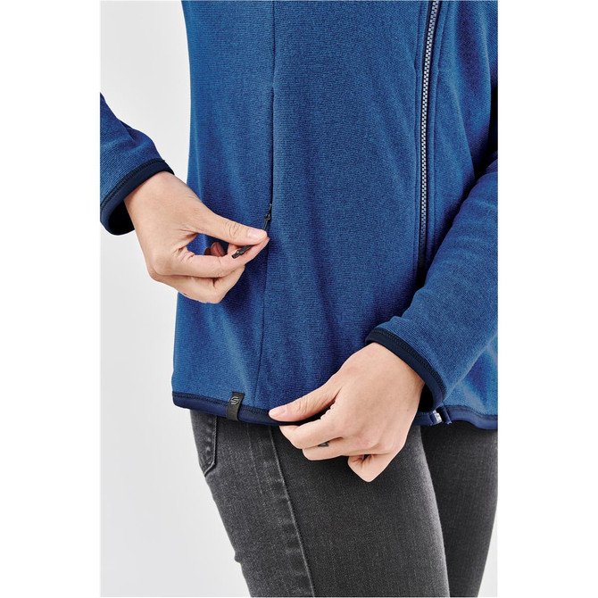A close-up of a person adjusting the zip on a blue Women's Novarra Full Zip Jacket, featuring a logo.