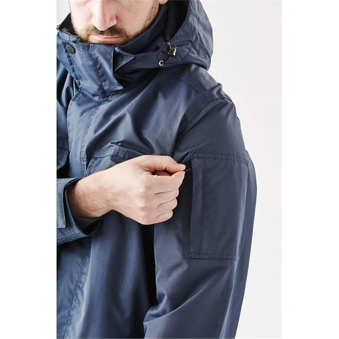 A navy blue men's jacket features a hood and multiple pockets, including an arm pocket. It has a logo.