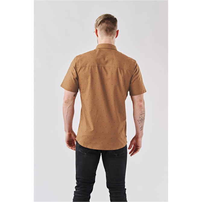 A short-sleeved, button-up shirt in tan with a patterned design, featuring a collar and a logo on the back.