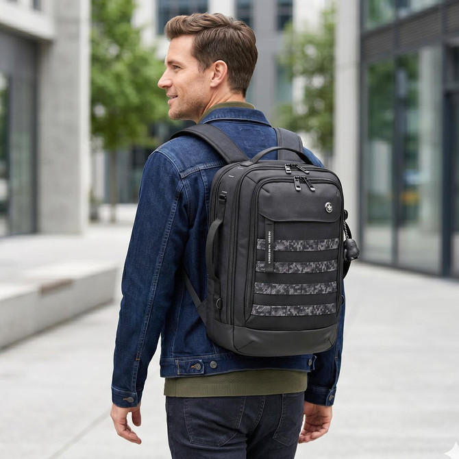 A man wearing a denim jacket carries a black Swissdigital Berg L Backpack with a patterned front in an urban setting.