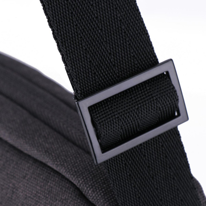 A black shoulder strap buckle featuring a textured fabric. The strap connects to a dark grey bag.