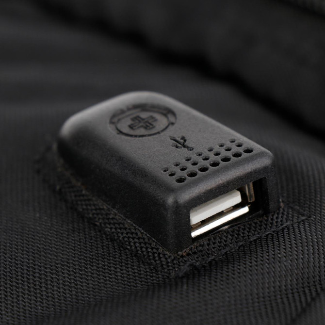 A close-up of a black USB port attached to a backpack, featuring a small branding logo.
