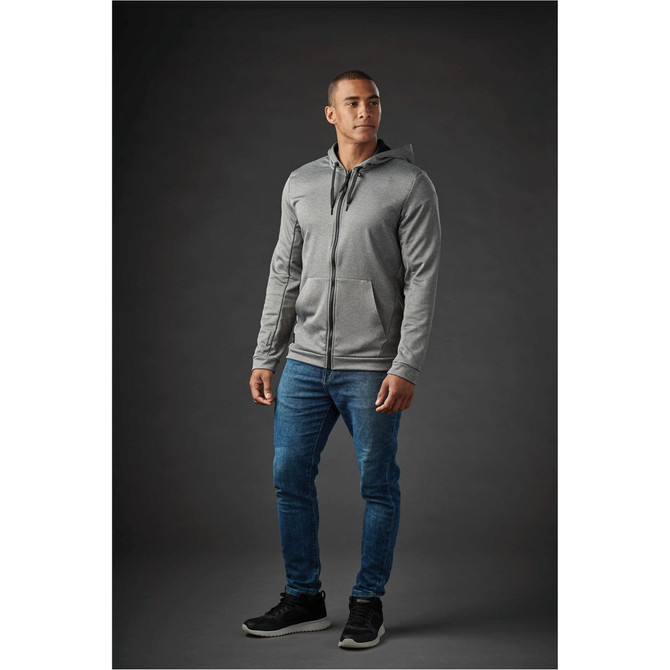 A grey zip-up hoody with a hood, paired with blue jeans, worn by a model against a dark background.
